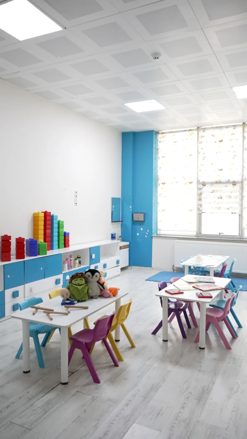 Sınıfın pencereye uzanan masaları ve renkli dolapları